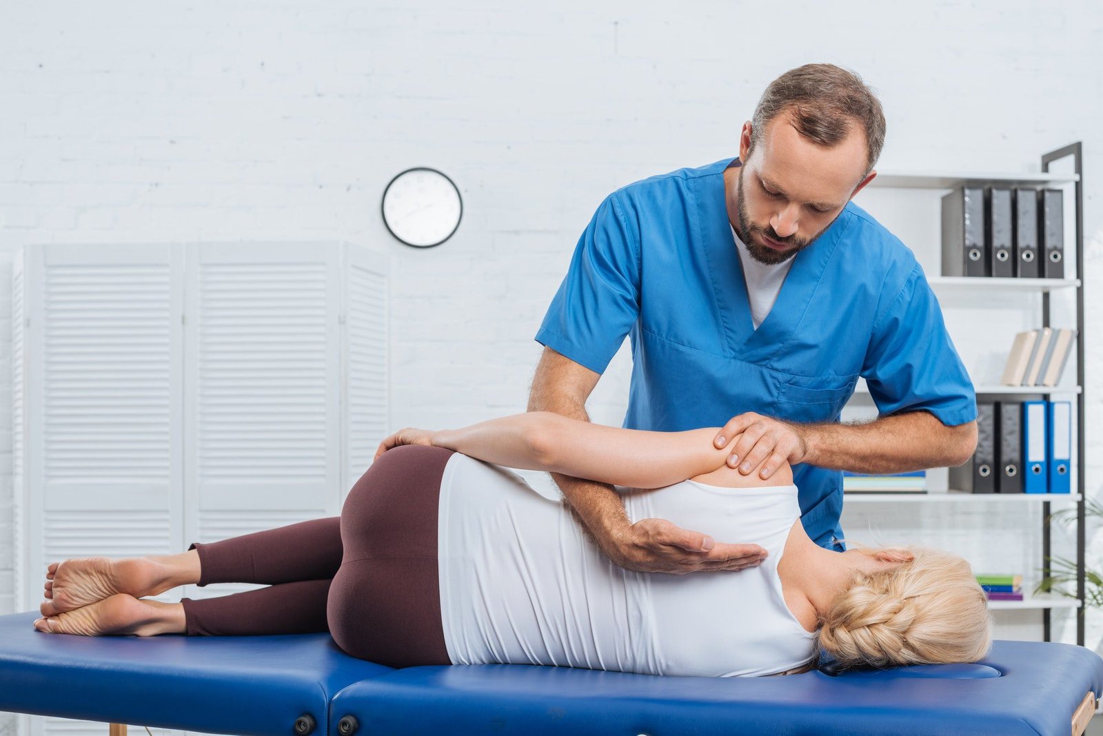 Osteopath massaging back of patient that lying on massage table in clinic