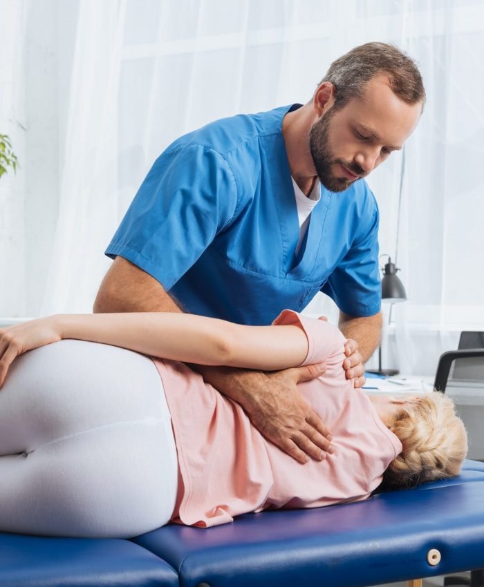 chiropractor massaging back of patient that lying on massage table in hospital