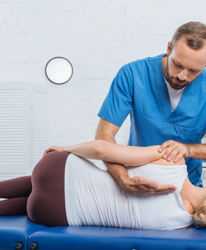 chiropractor massaging back of patient that lying on massage table in hospital Osteopath massaging back of patient that lying on massage table in clinic