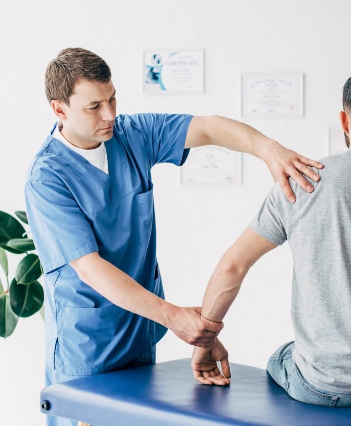 Physiotherapist massaging arm of patient on massage table in hospital Physiotherapist massaging arm of patient on massage table in hospital